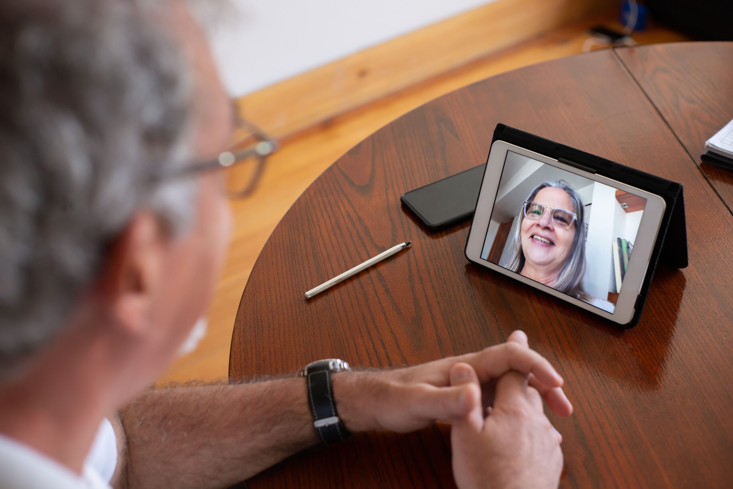 Older adult using a tablet for a video call with support nearby