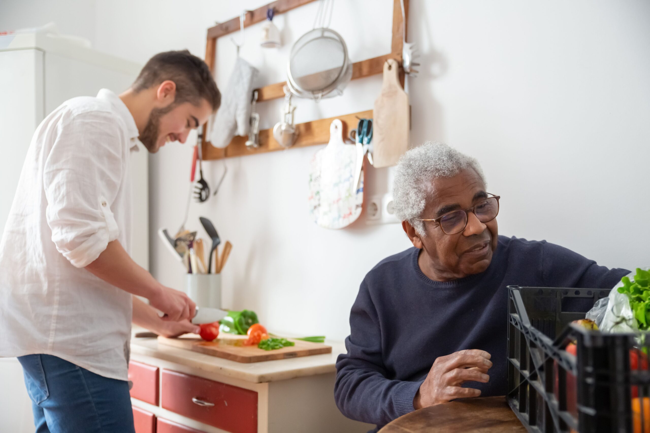 Older adult and companion preparing fresh vegetables together